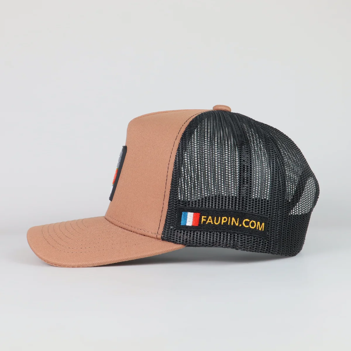 Side view of the tan patch trucker cap showing black mesh and side branding