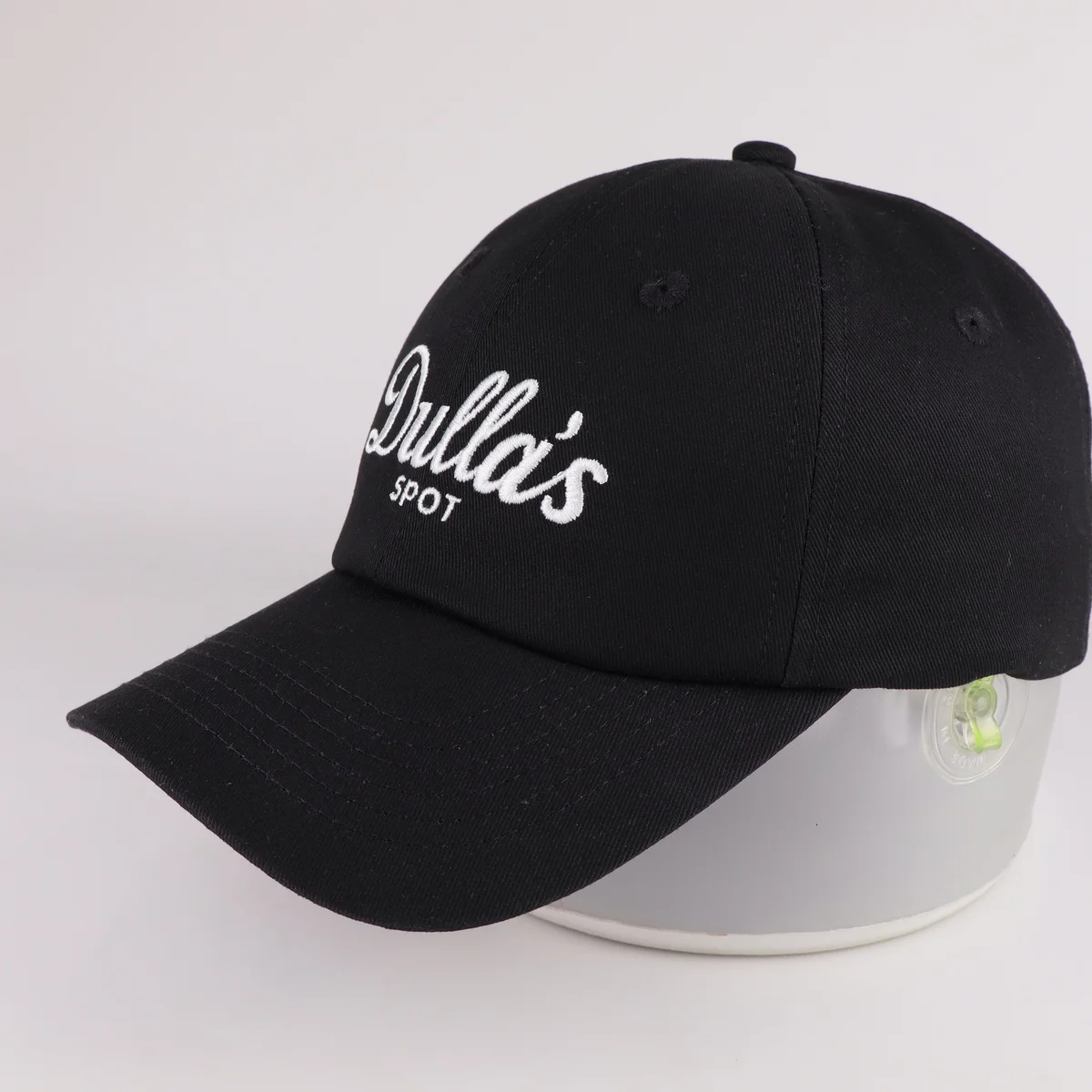 Black script-embroidered cap photographed from the opposite front side