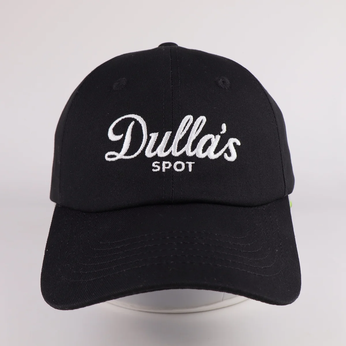 Black baseball cap with white script logo above the curved visor
