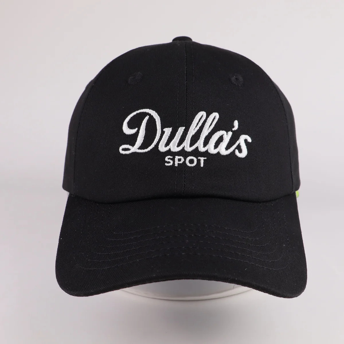 Black curved-brim baseball cap with white script embroidery, front view